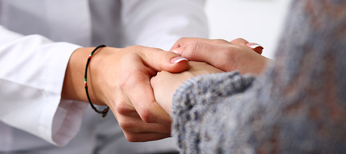 Mãos de uma médica segura as mãos de uma paciente