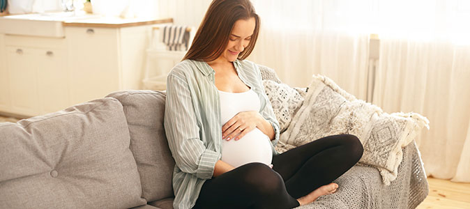 Mulher grávida sentada no sofá de casa