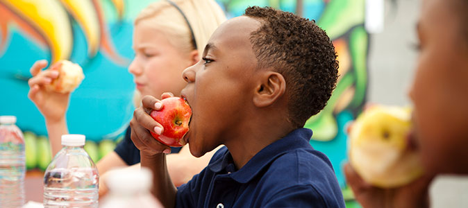 um menino come uma maça
