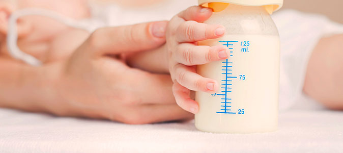 bebê e segurando leite materno