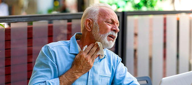 Imagem de um homem de idade colocando um papel em sua gargante